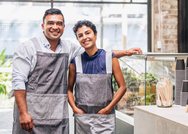 Small business entrepreneurs at their cafe Business partners. Portrait at counter of their new business enterprise. apron photos stock pictures, royalty-free photos & images