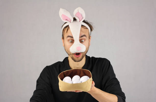 istock man in the mask Easter rabbit surprised looking at the eggs in h 909998946