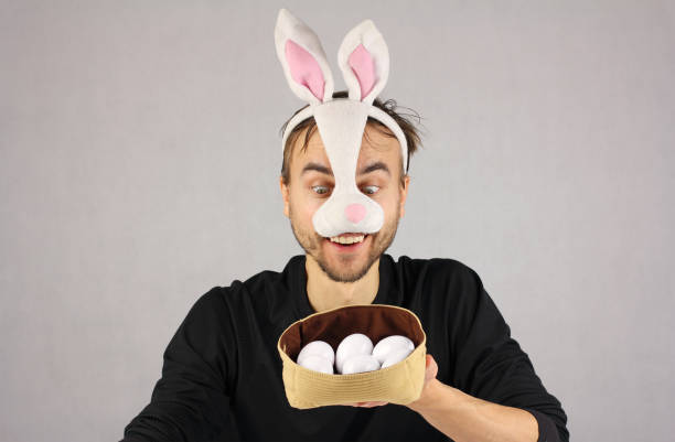 istock man in the mask Easter rabbit looking at the eggs in hat 909999104
