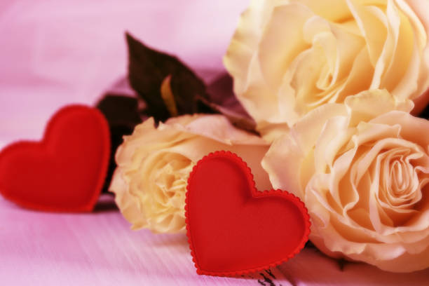 istock Roses and red hearts on a white wooden background 910002384