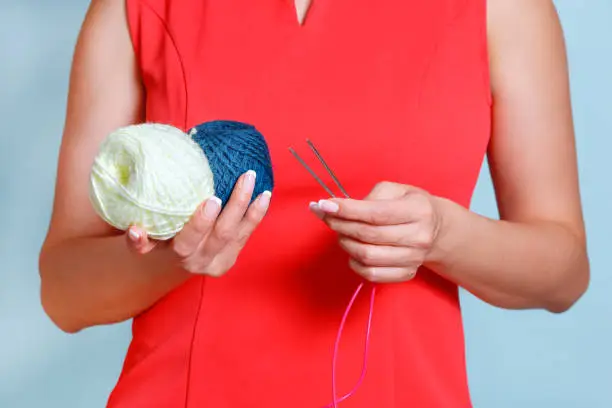 Puffs of wool as a symbol of hobby knitting in female hands.