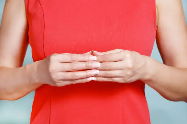 Female hands on a blouse background. Woman in red blouse on a turquoise background.