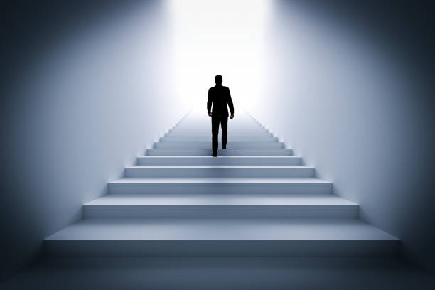 istock Businessman climbing the stairs towards light. 910009826