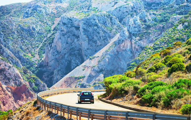 Car on road at Buggerru in Carbonia Iglesias Sardinia Car on road with idyllic hills and mountains at Buggerru in Carbonia-Iglesias, Sardinia, Italy Buggerru stock pictures, royalty-free photos & images