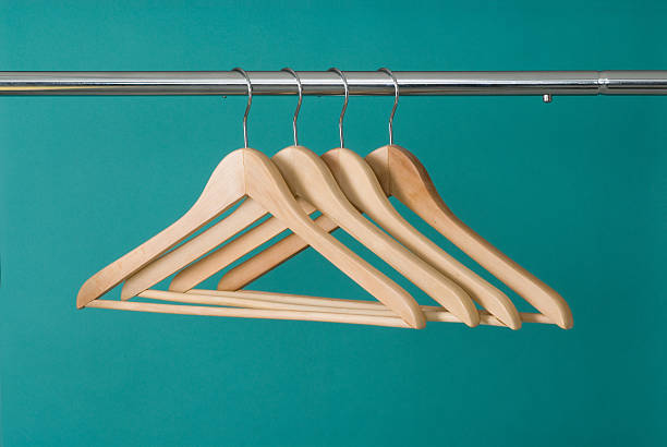 Hangers On Pole Four wooden hangers on chrome pole with a green background. coathanger stock pictures, royalty-free photos & images