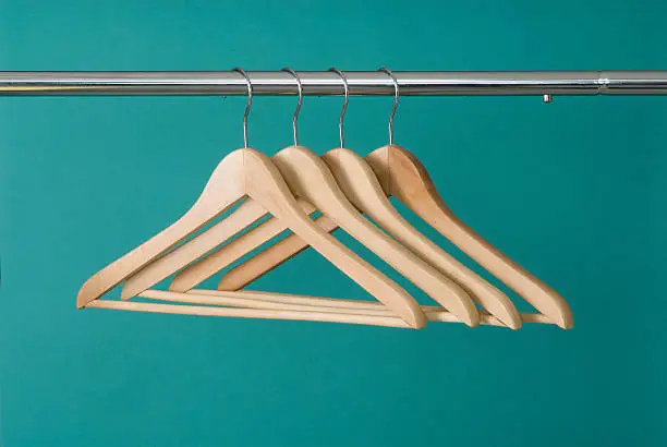 Four wooden hangers on chrome pole with a green background.