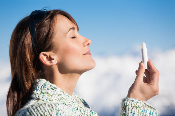 istock woman in winter applying solar cream on her lips 910017380