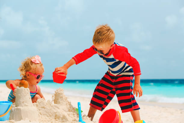 istock little boy and girl play with sand on beach 910017782