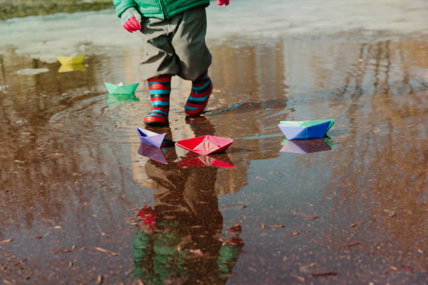 istock child playing with paper boats in water puddle 910019666