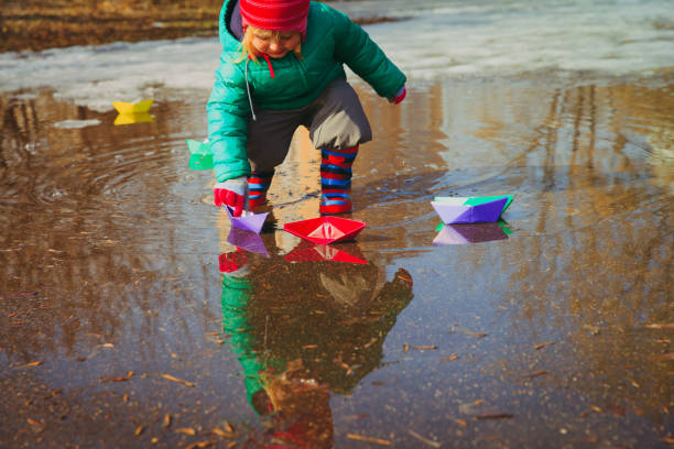 istock child playing with paper boats in water puddle 910020600