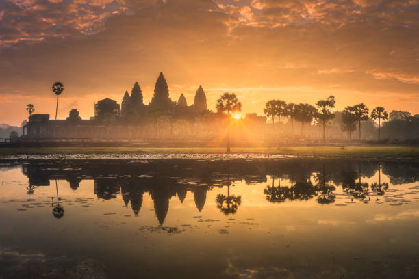 Sunrise view of ancient temple complex Angkor Wat Siem Reap, Cambodia Sunrise view of popular tourist attraction ancient temple complex Angkor Wat with reflected in lake Siem Reap, Cambodia angkor stock pictures, royalty-free photos & images