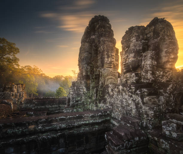 vista do nascer do sol do antigo templo bayon angkor com pedra enfrenta siem reap, camboja - cambodia monk buddhism angkor wat - fotografias e filmes do acervo