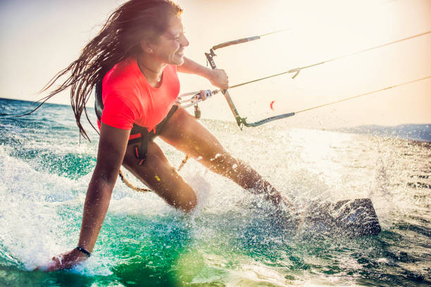 sorridente giovane kiteboarder femminile sul mare - extreme sports foto e immagini stock