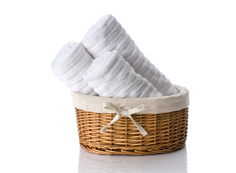 Three white hand towels in a wicker basket.