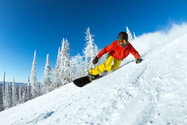 Very fast snowboarder slides at ski slope stock photo