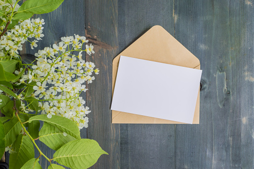 Mockup white greeting card and envelope with white spring flowers and rustic wooden background