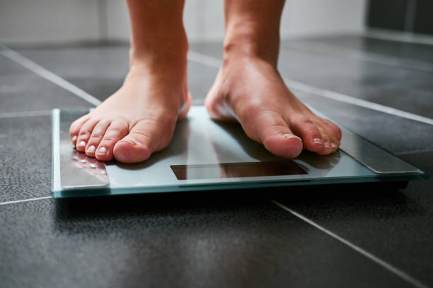 istock Female feet with weight scale in the bathroom 910049862