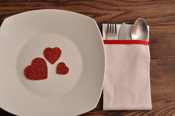 istock Cutlery displayed in a white napkin next to a white plate decorated with red hearts 910056112