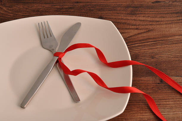 istock A fork an knife tied together with a red ribbon displayed on a white plate 910056536