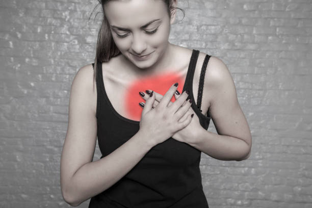 istock A young woman is holding her chest, Possible heart attack, first symptoms, front view 910062102