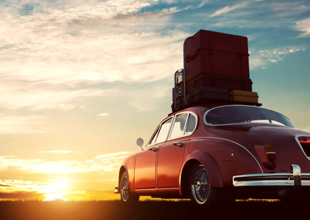 夕暮れ時の屋根のラックに荷物をレトロな赤い車。旅行、休暇の概念。 - trunk luggage old fashioned retro revival ストックフォトと画像