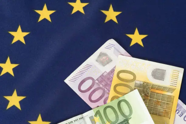 Photo of Flag of the European Union EU and Euro banknotes