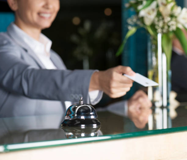 Service Business Caucasian female is giving key for hotel room to guest at reception desk. hotel reception hotel service technology stock pictures, royalty-free photos & images