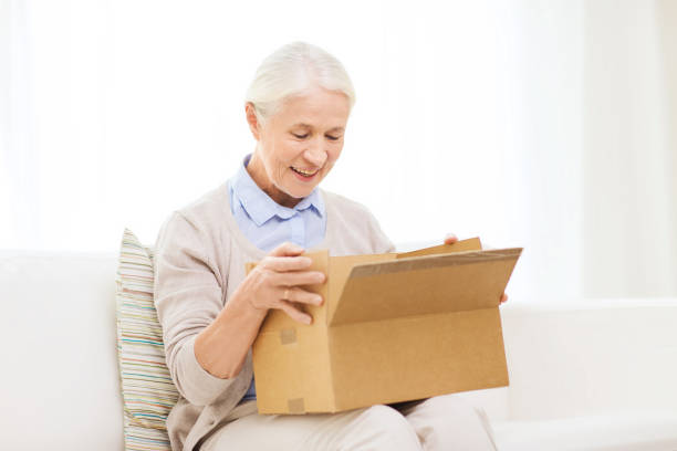 istock happy senior woman with parcel box at home 910070760