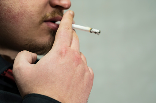 man smoking cigar on grey background