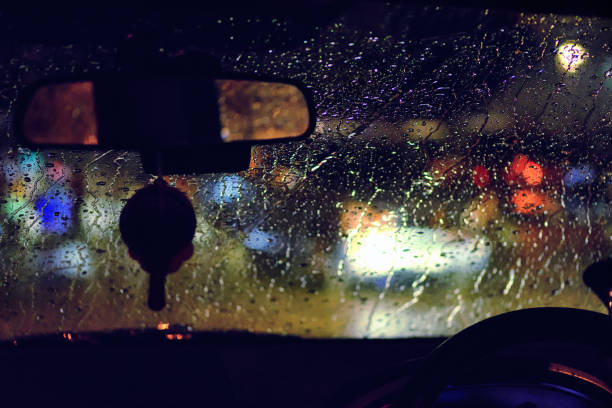 istock Abstract traffic in raining day. View from car seat. Background in retro filter. Road view through car window with rain drops at night 910081118
