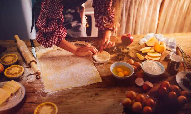 Close-up of woman's hands making apple pies in rustic kitchen
