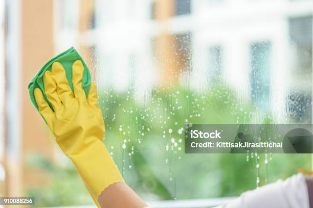 Woman Housekeeper Cleaning The Mirror With Green Cloth Stock Photo - Download Image Now