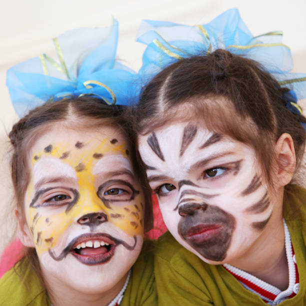 istock Little girls (twins) with faces painted like cheetah and zebra 910091354
