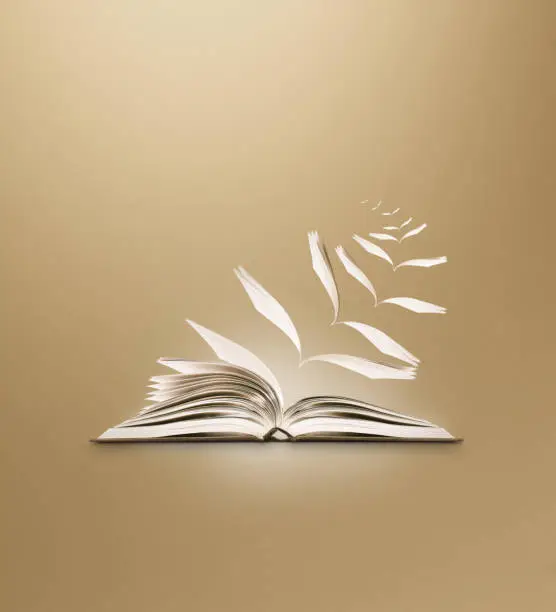 conceptual image of a reading book opening and pages flying away as if imagined in a story, on a subtle brown background with extended areas for copy space