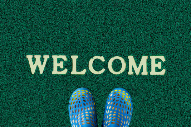 istock Man feet standing on green Welcome carpet 910104520