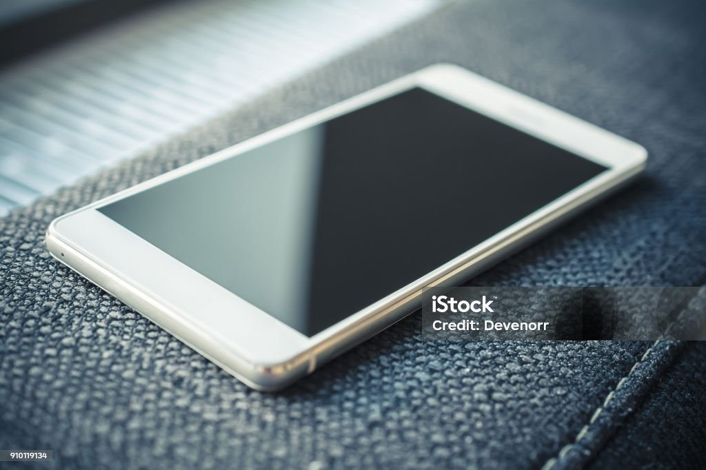 Smartphone With Reflection Lying On The Armrest Of A Couch Table Stock Photo