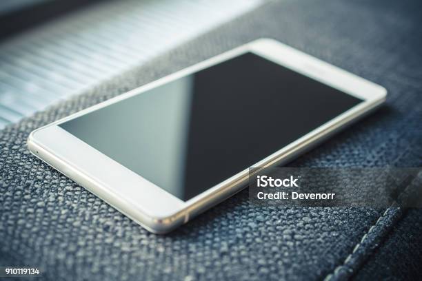Smartphone With Reflection Lying On The Armrest Of A Couch Stock Photo - Download Image Now