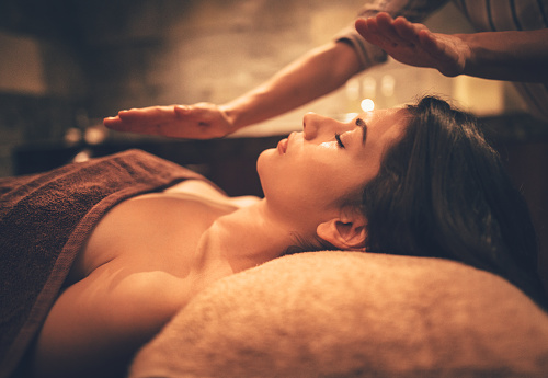 Woman lying down and relaxing with wellness massage from professional therapist at wellnes spa salon