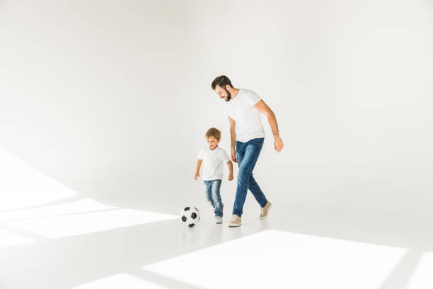 father and son with soccer ball full length view of happy father and son playing together with soccer ball on white together for yes stock pictures, royalty-free photos & images