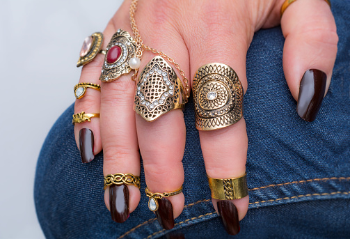 Overweight ringed mature woman hand on jeans rings on every finger