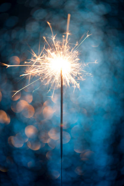 Close up of sparkler on blue background. This file is cleaned and retouched.