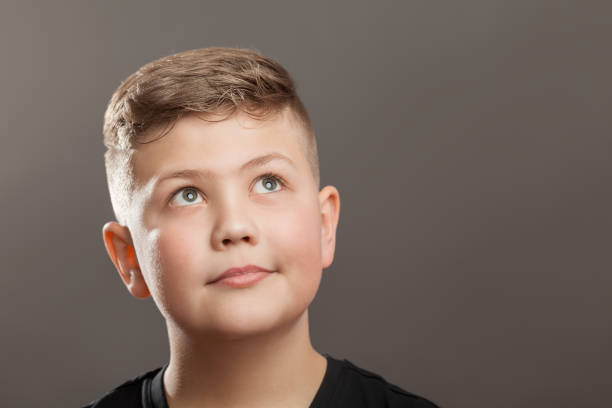 istock Teenager boy looking up on grey background 910132278