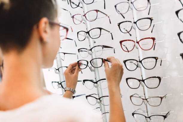 Woman in optical optical store Beautiful middle age woman choosing a glasses in optician store. ophthalmologist photos stock pictures, royalty-free photos & images