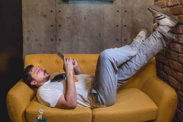 Man resting on the sofa Young man lying on the yellow sofa, spending his leisure time resting. tired after work stock pictures, royalty-free photos & images