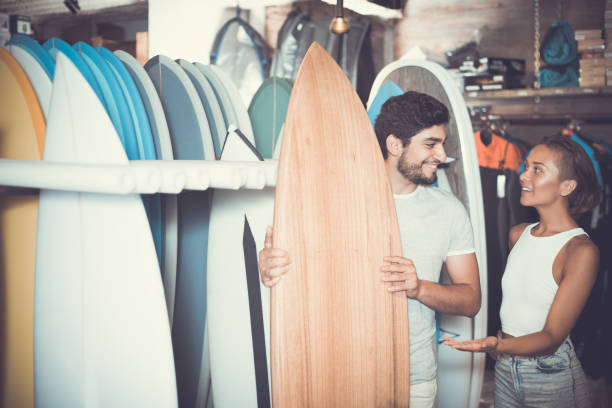 istock man and woman choosing surfboards 910139474