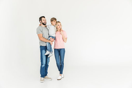 happy parents with son standing together and looking away isolated on white