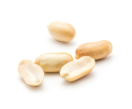 Three shelled peanuts (raw and without husk) and two cracked halves isolated on white background