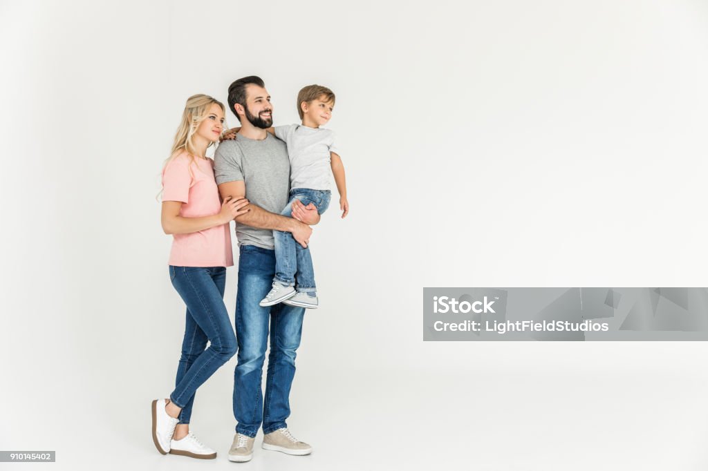 happy parents with son cute happy little boy with mother and father standing together and looking away isolated on white Family Stock Photo