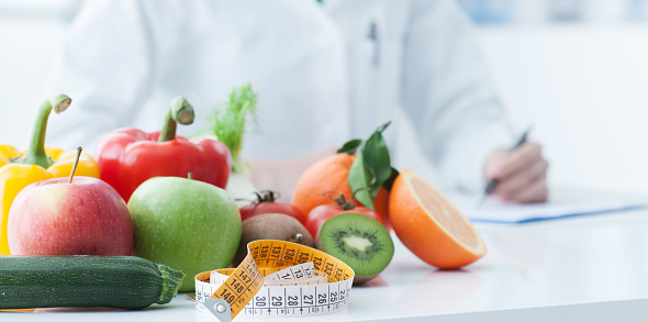 Nutritionist desk with healthy fruit, vegetables and a measuring tape, weight loss and diet concept