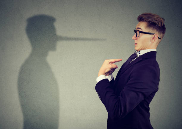 Man pointing at himself while lying Side view of man in suit pointing at himself looking at shadow with long nose of a liar. bluff stock pictures, royalty-free photos & images